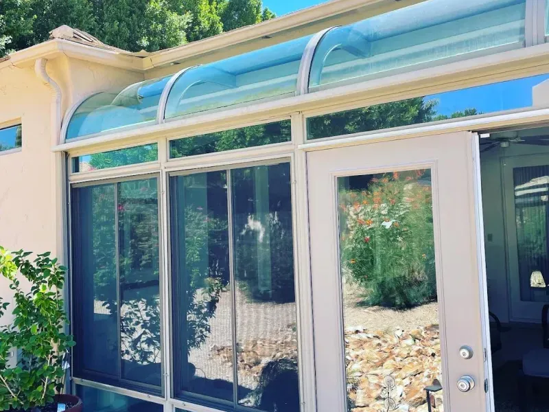 A sunroom with a glass roof and sliding glass doors.