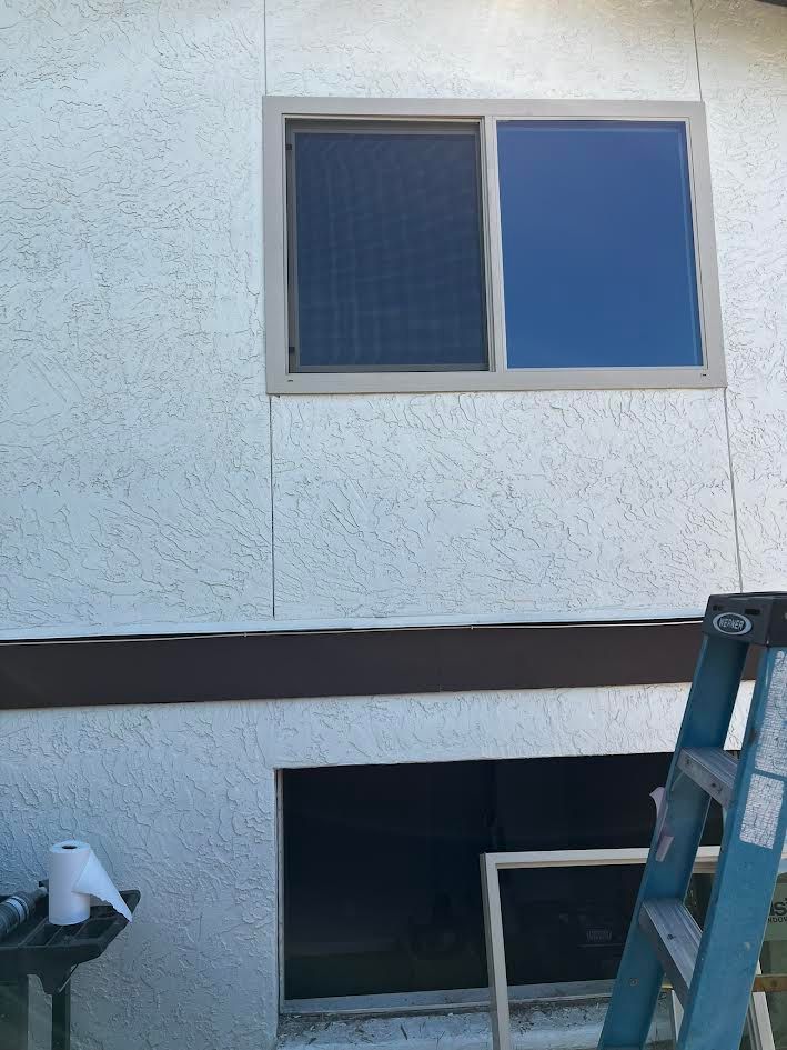 A ladder is sitting next to a window on the side of a building.