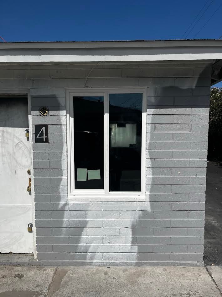 A gray brick building with a white window and a white door.