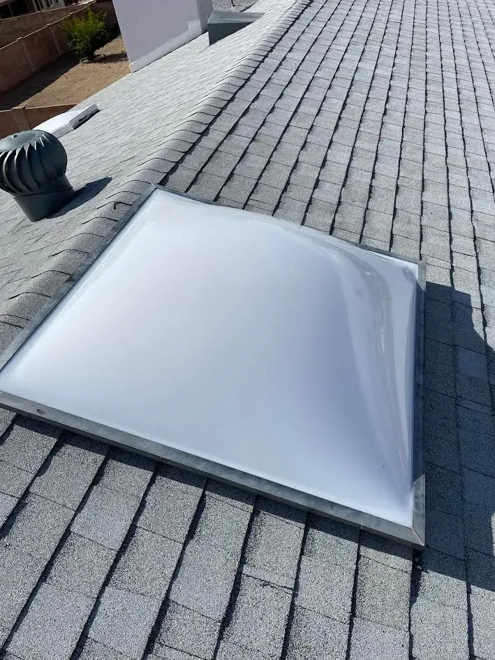 A white skylight is sitting on top of a brick roof.