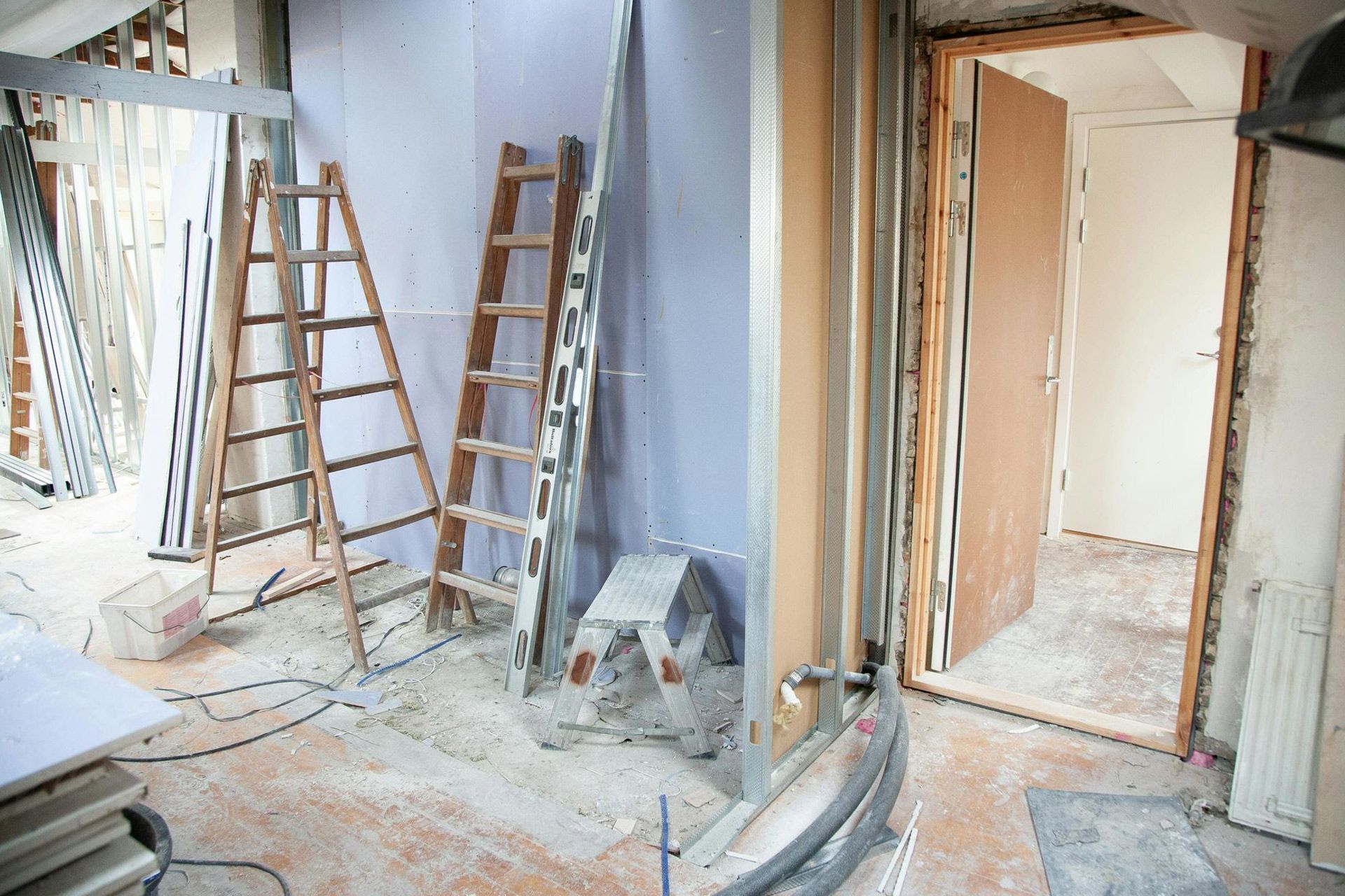 Interior renovation with ladders, tools, and unfinished walls in a dusty room