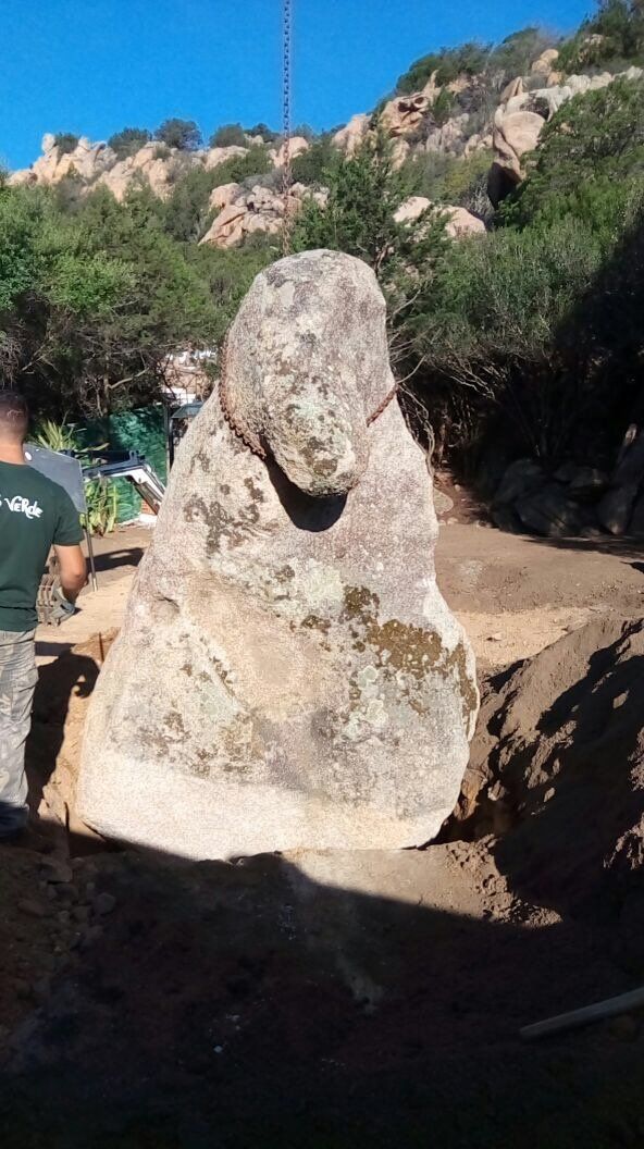 Una grande roccia si trova nel mezzo di un campo sterrato.