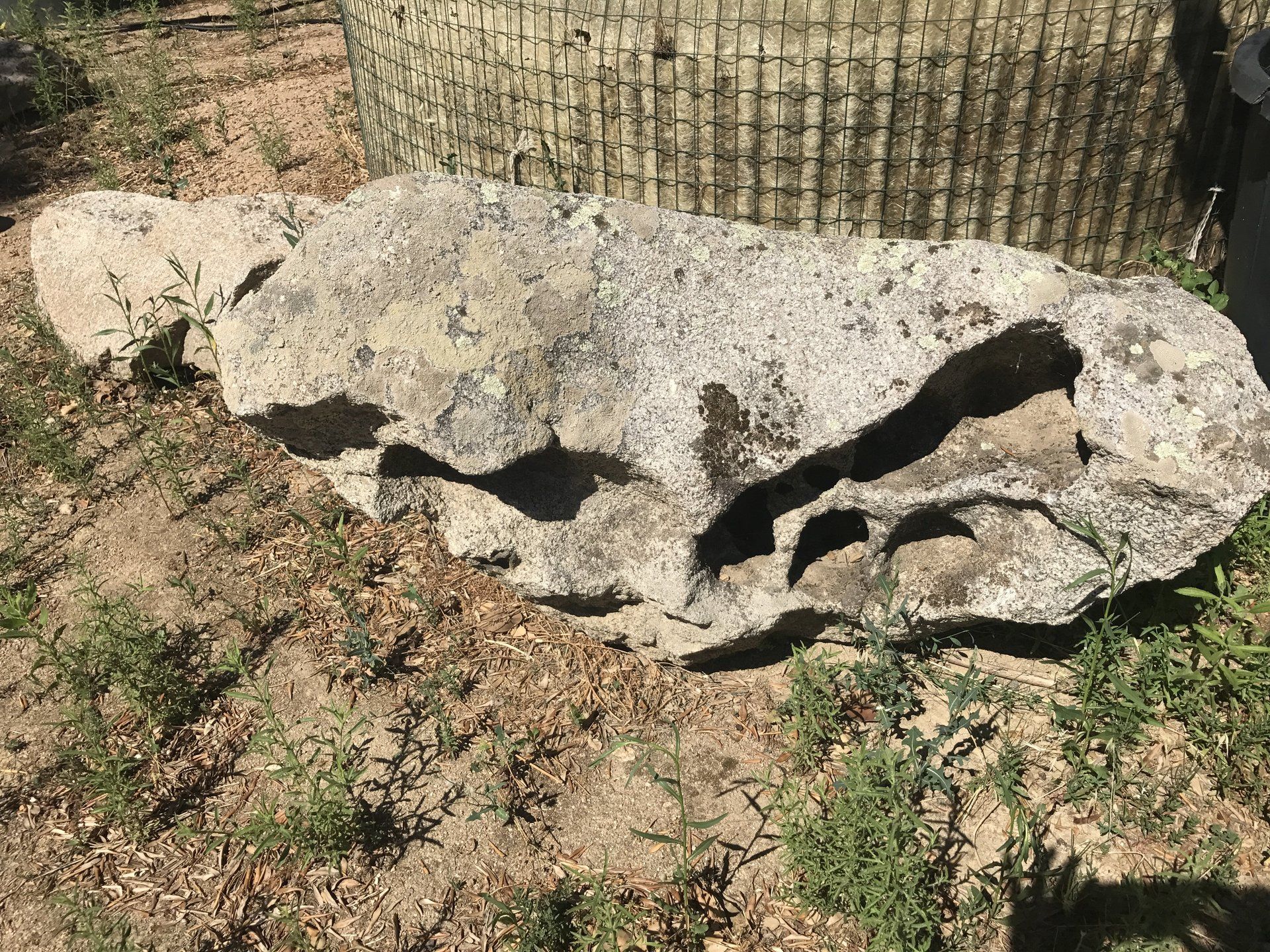 Una grande roccia giace a terra accanto a un pneumatico.