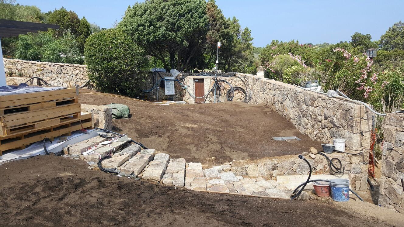 Un grande mucchio di terra si trova in cima a una collina accanto a un muro di pietra.
