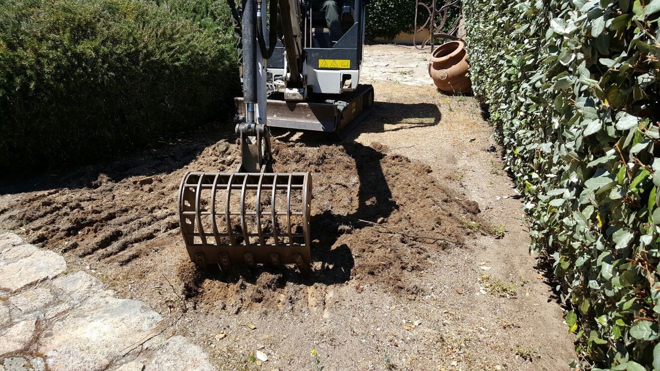 Un piccolo escavatore sta lavorando su una strada sterrata.