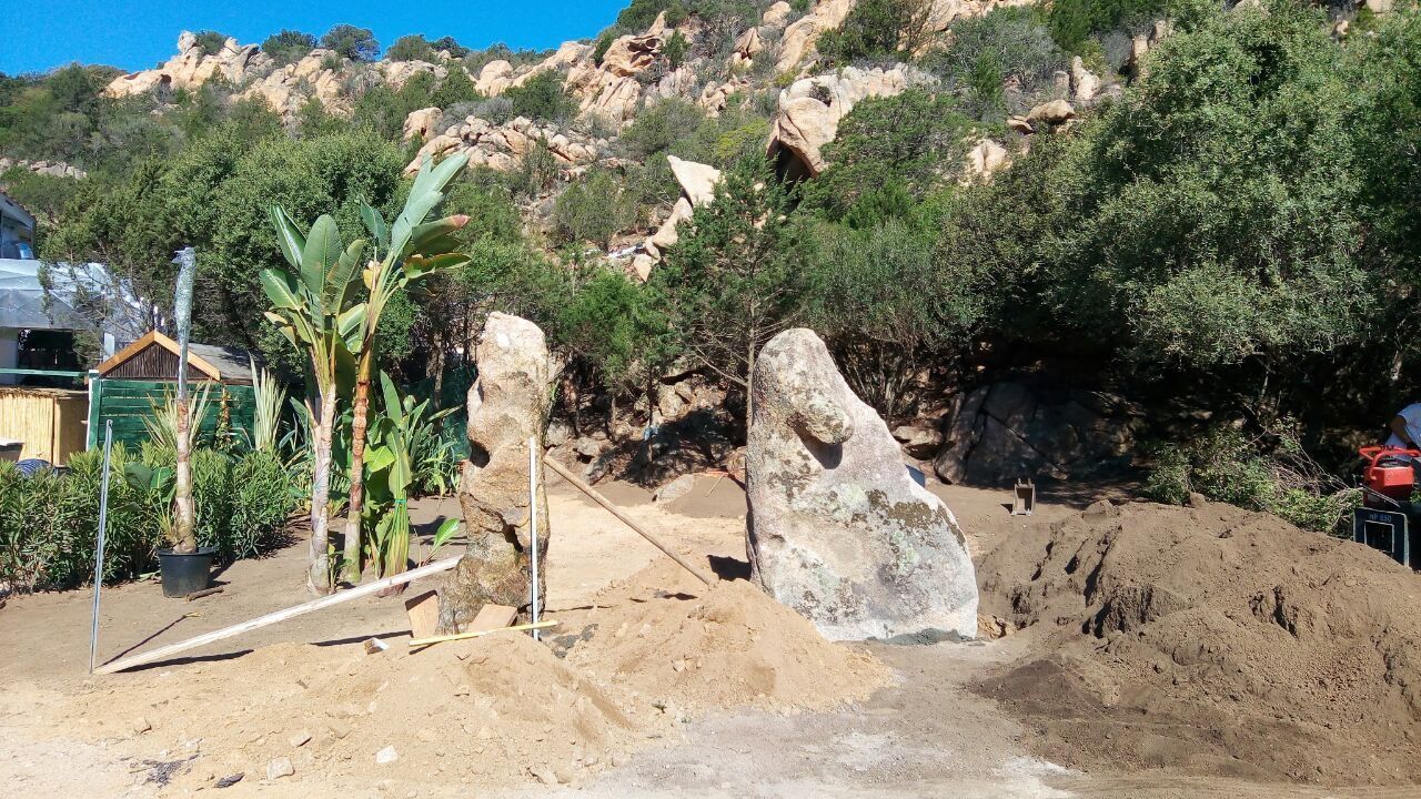 A large rock stands in the middle of a mound of earth.
