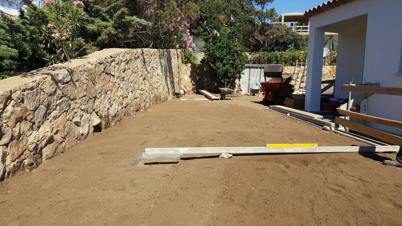 Accanto a un muro di pietra si sta costruendo una casa bianca.