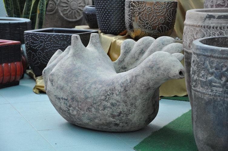 Su un tavolo insieme ad altri vasi è seduta la statua di un uccello