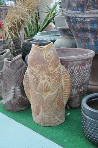 Una statua di un pesce è circondata da vasi e piante.