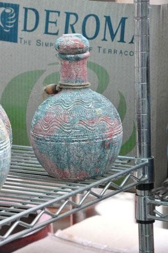 Una bottiglia è posata su uno scaffale di metallo davanti a una scatola di cartone con la scritta derom