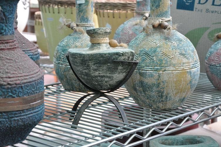 Su uno scaffale di metallo è appoggiato un mazzo di vasi