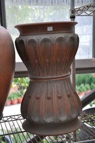 Un grande vaso marrone è appoggiato su uno scaffale di metallo.