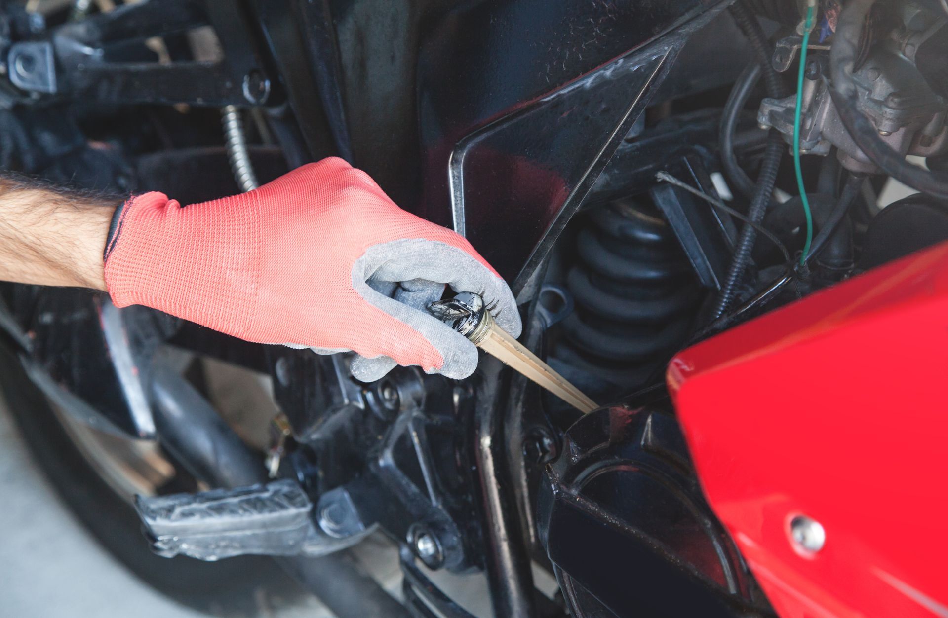 Person in Red Gloves Working on A Motorcycle Engine with A Tool — Wallsend Automotive in Maryland, NSW