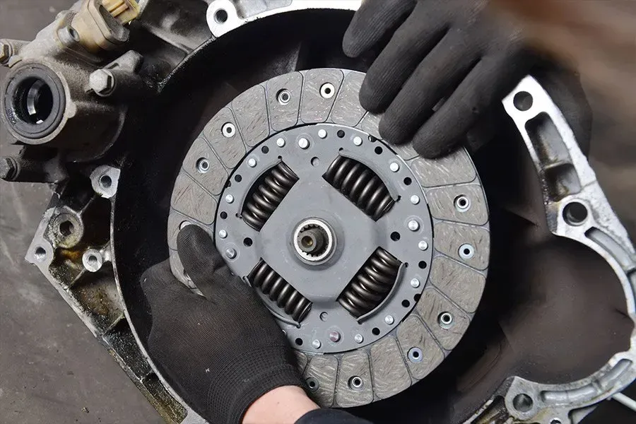 Hands in Black Gloves Installing a Clutch Disc Into a Car Transmission — Wallsend Automotive in Maryland, NSW