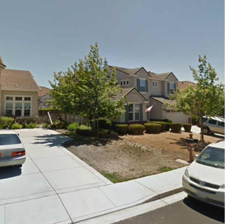 A white car is parked in front of a house