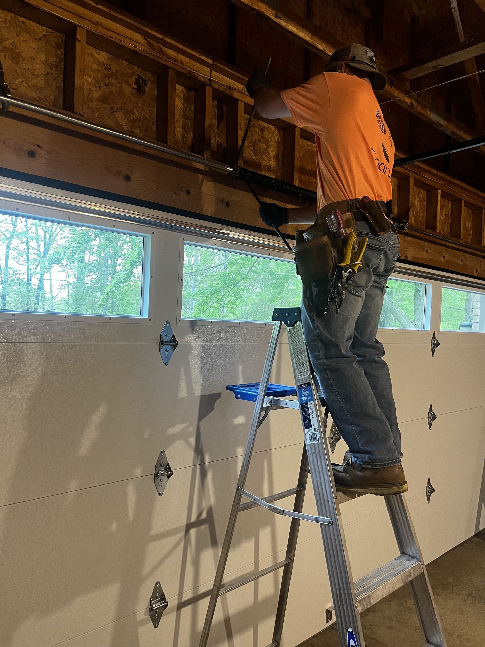 A man is working on a garage door opener in a garage.