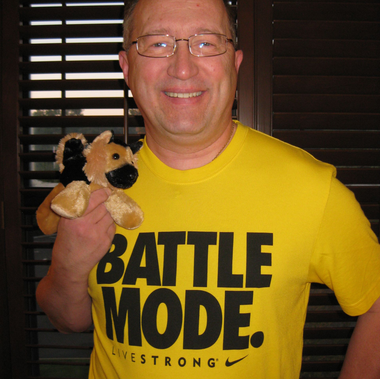 Man with glasses and Morgan Freeman holding microphones, smiling in front of greenery.