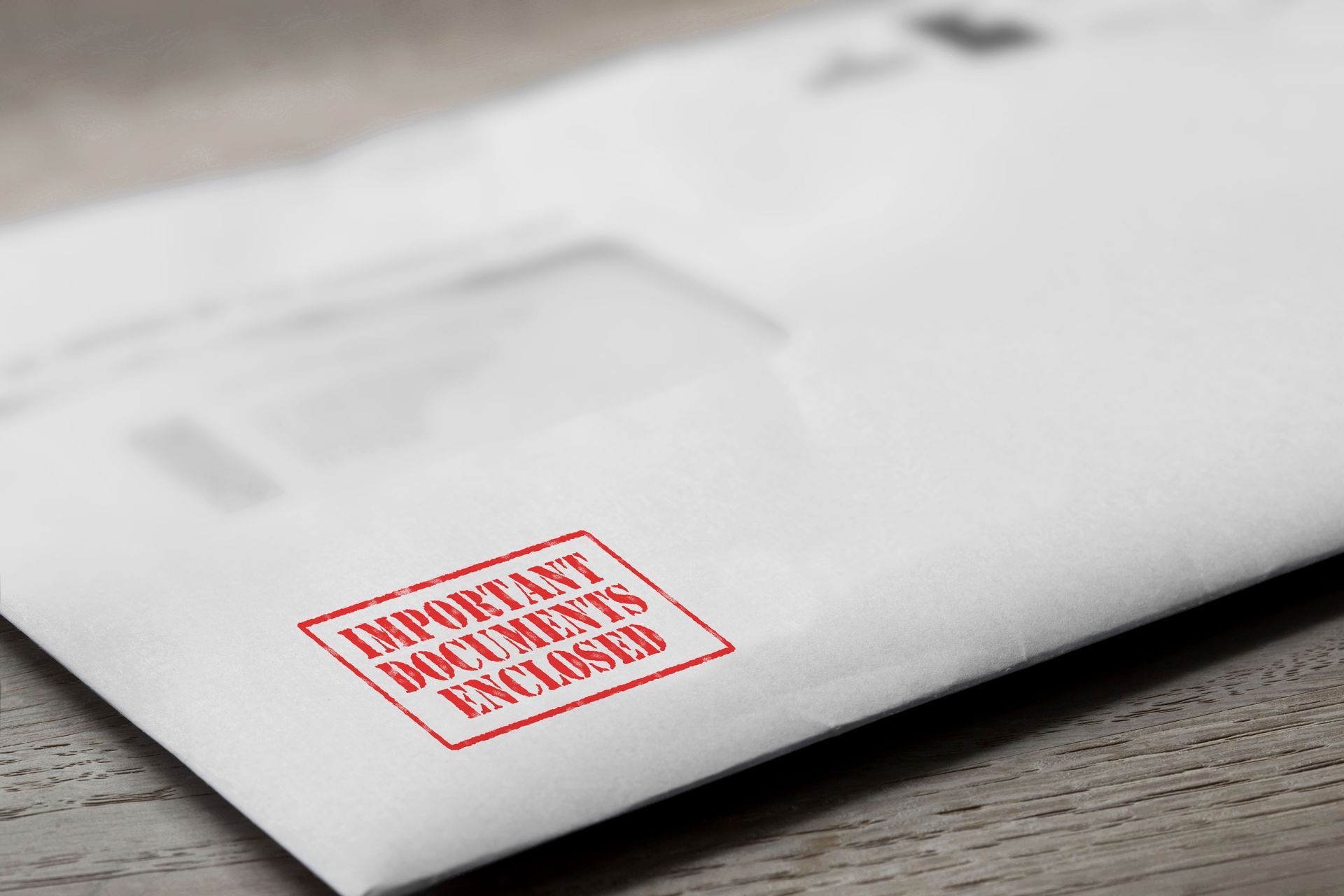 White envelope on a desk with a red stamp reading IMPORTANT DOCUMENTS ENCLOSED.