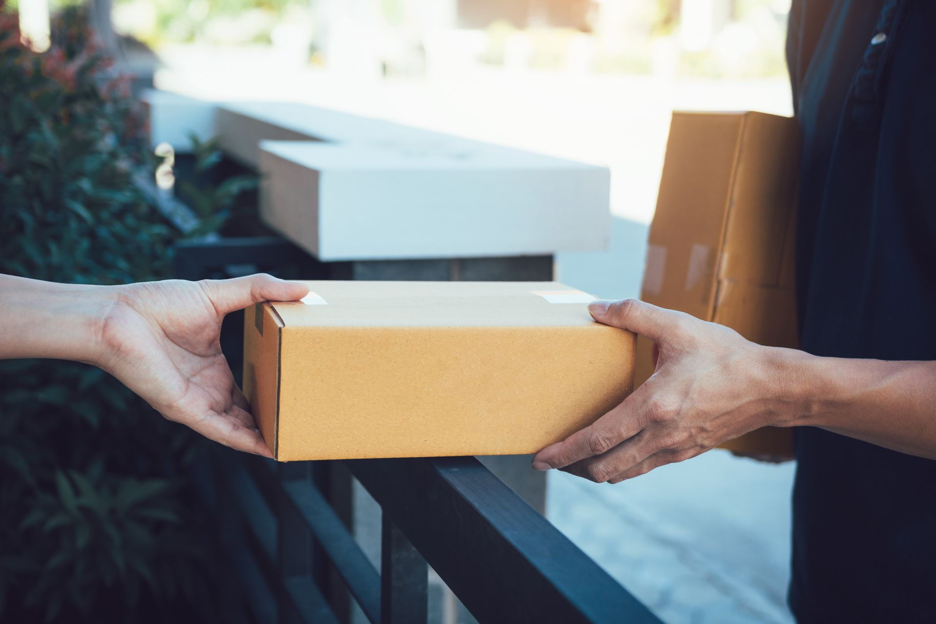 Hands exchanging a cardboard package at a doorstep