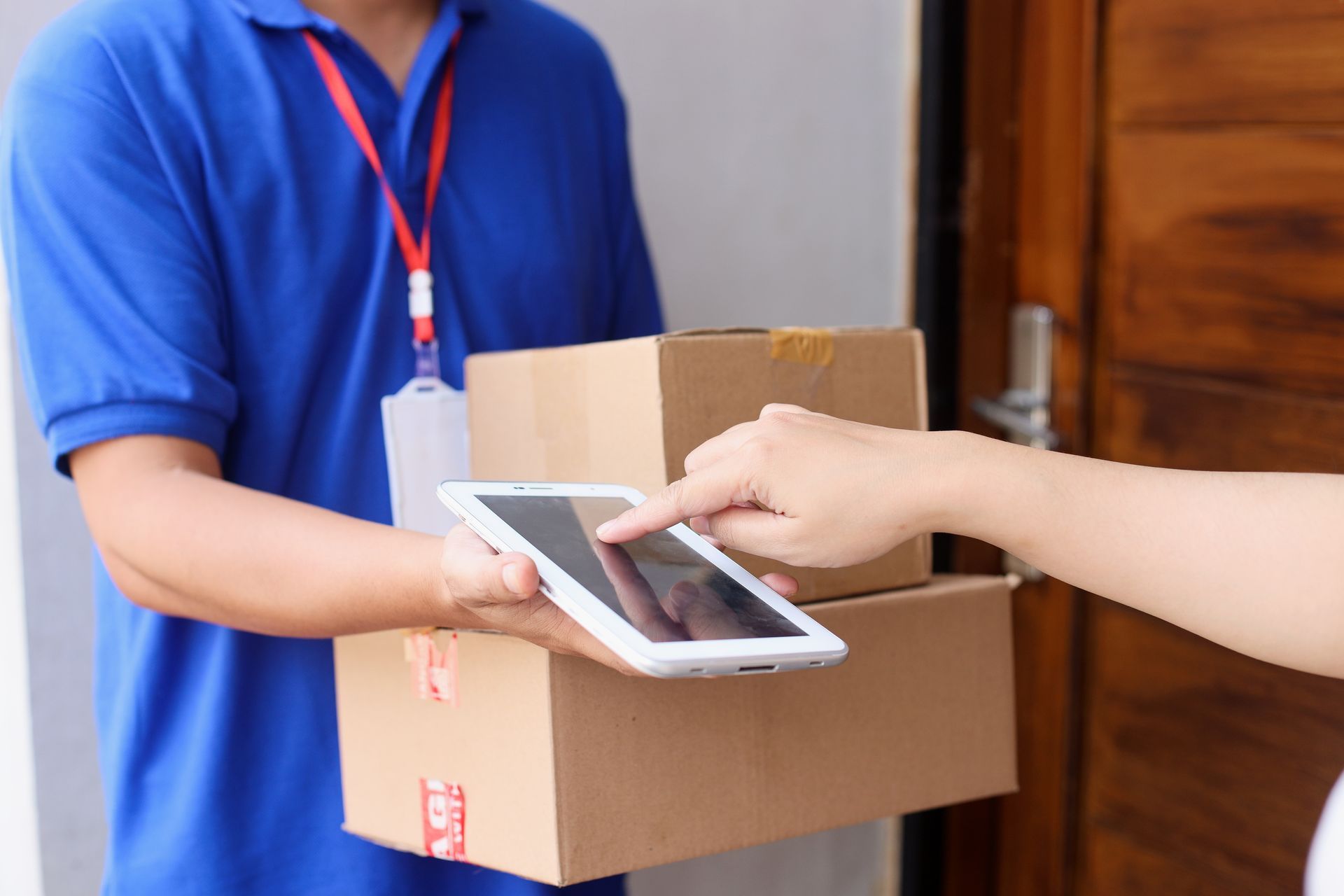 Person scanning a tablet on a cardboard package being handed over at a doorway