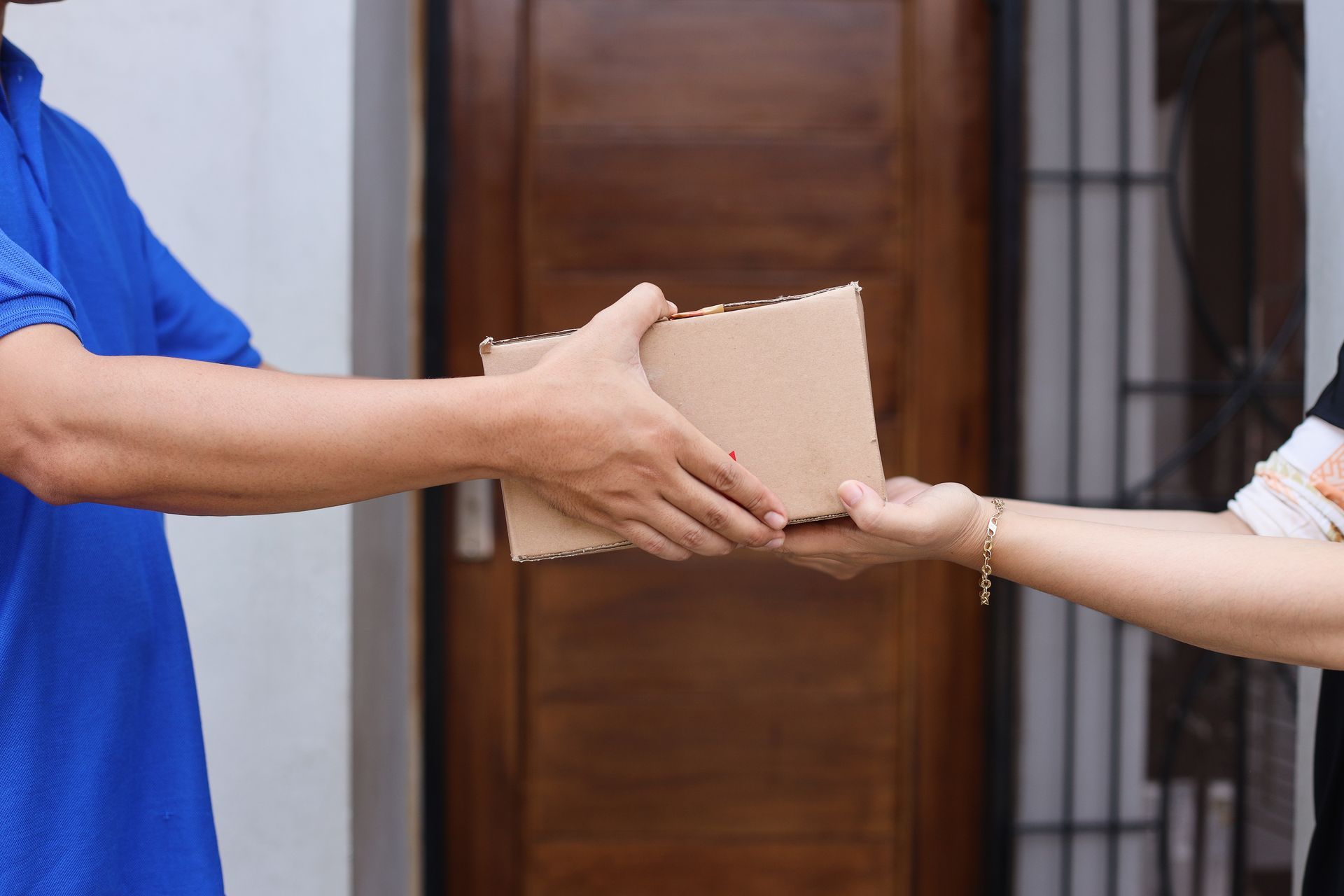 Hands exchanging a cardboard package at a doorway
