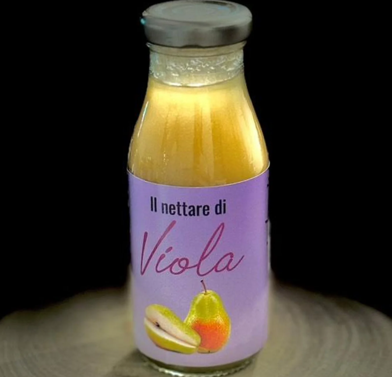 Una bottiglia di vetro contenente succo giallo pallido con un'etichetta viola recante la scritta 