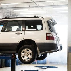 A white suv is sitting on a lift in a garage
