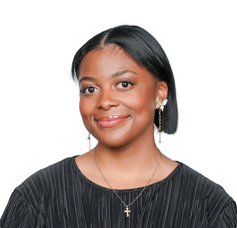 Smiling portrait of a person in a black top, wearing earrings and a cross necklace, against a white background