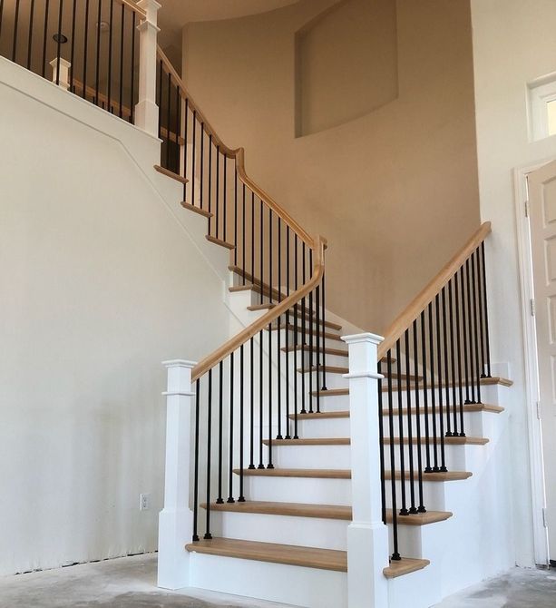 Traditional light stained maple treads and handrailing with white painted dressed posts fluted posts and satin black plain bar iron balusters