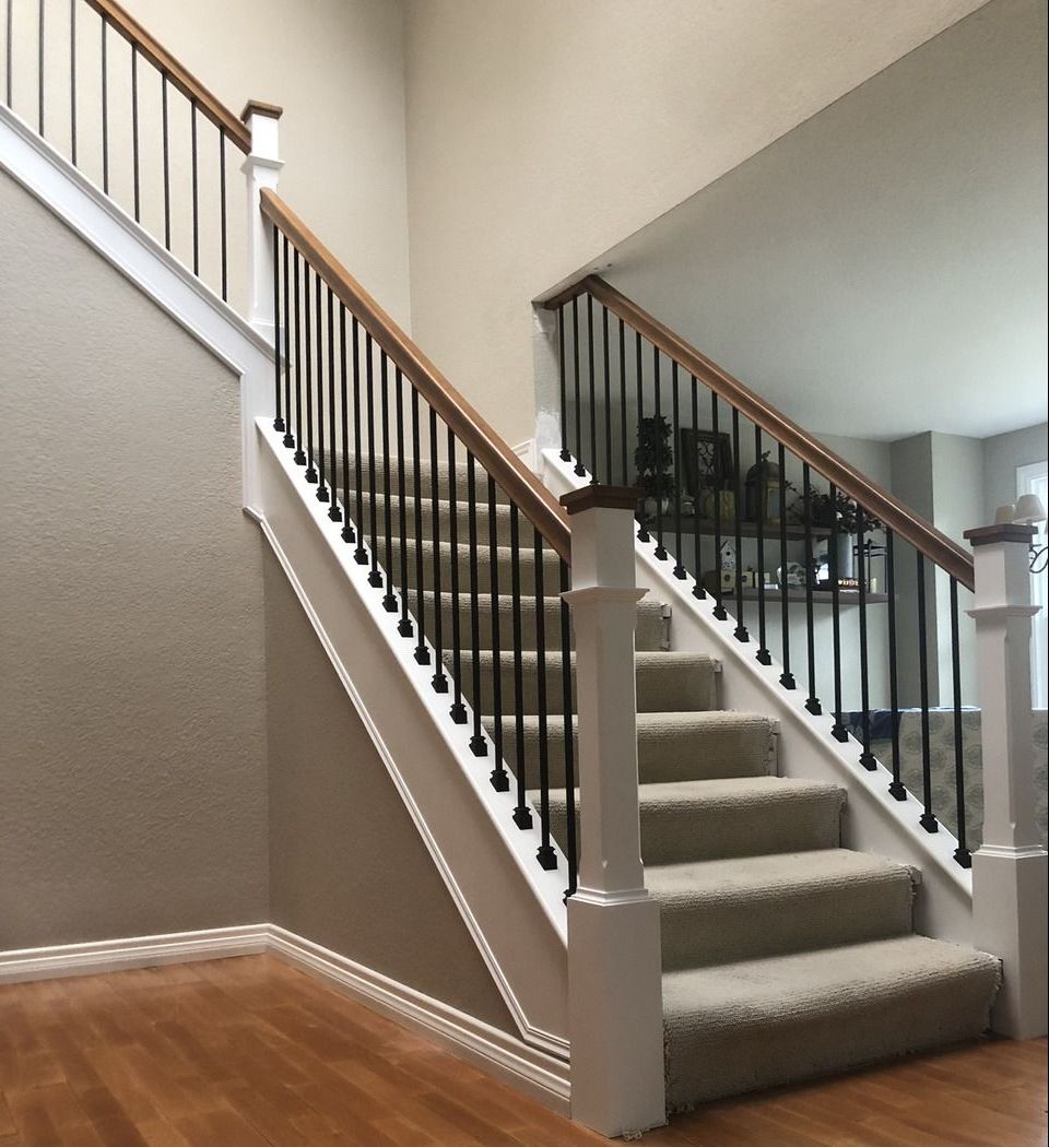 Traditional rich colored maple railing and white painted custom newel posts with black iron balusters