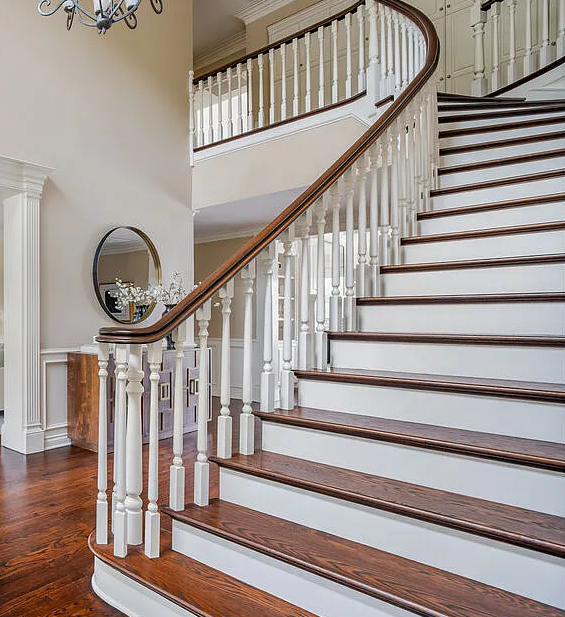 Traditional style staircase with over the post railing system with volute and white painted balusters