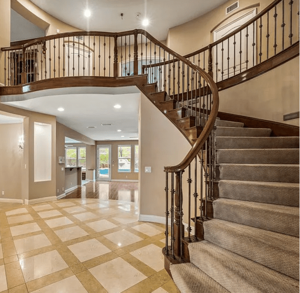 Curved staircase with stained wooden over the post handrailing and iron balusters