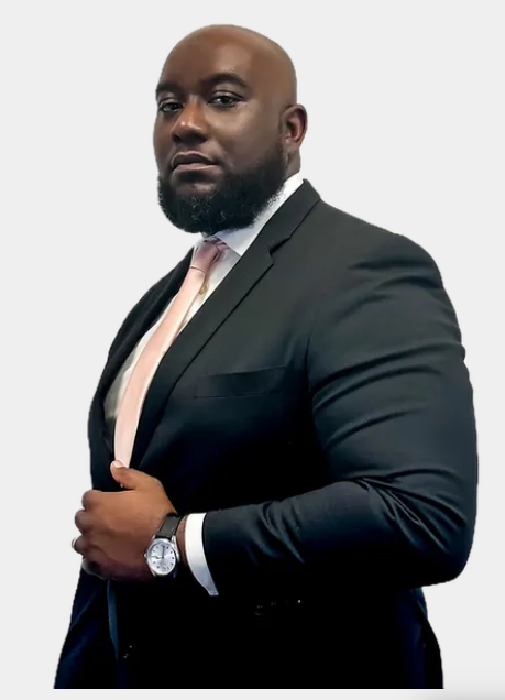 Woman with glasses, arms crossed, wearing a black blazer and dress, smiling.