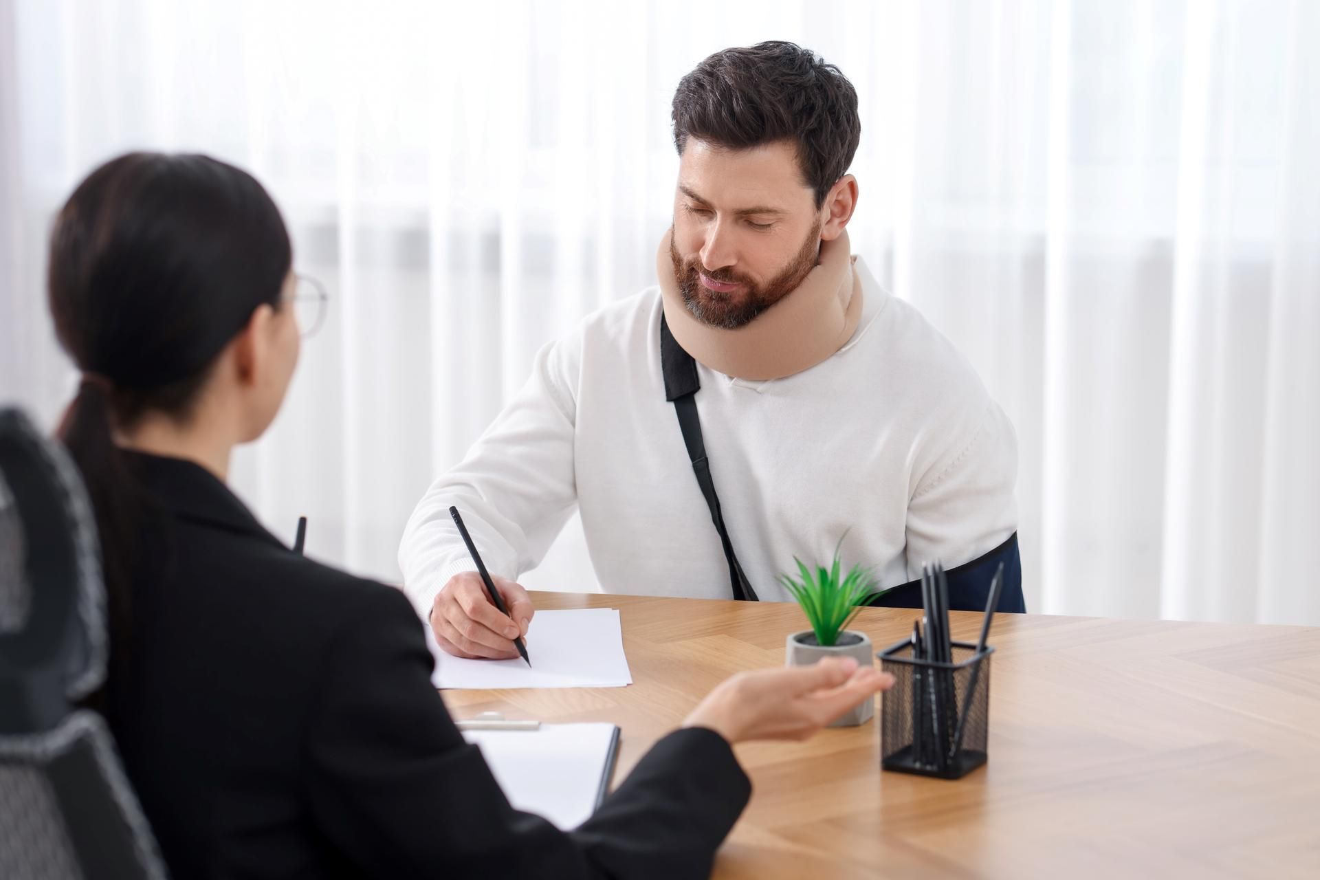 A man with a neck brace is sitting at a table talking to a woman.