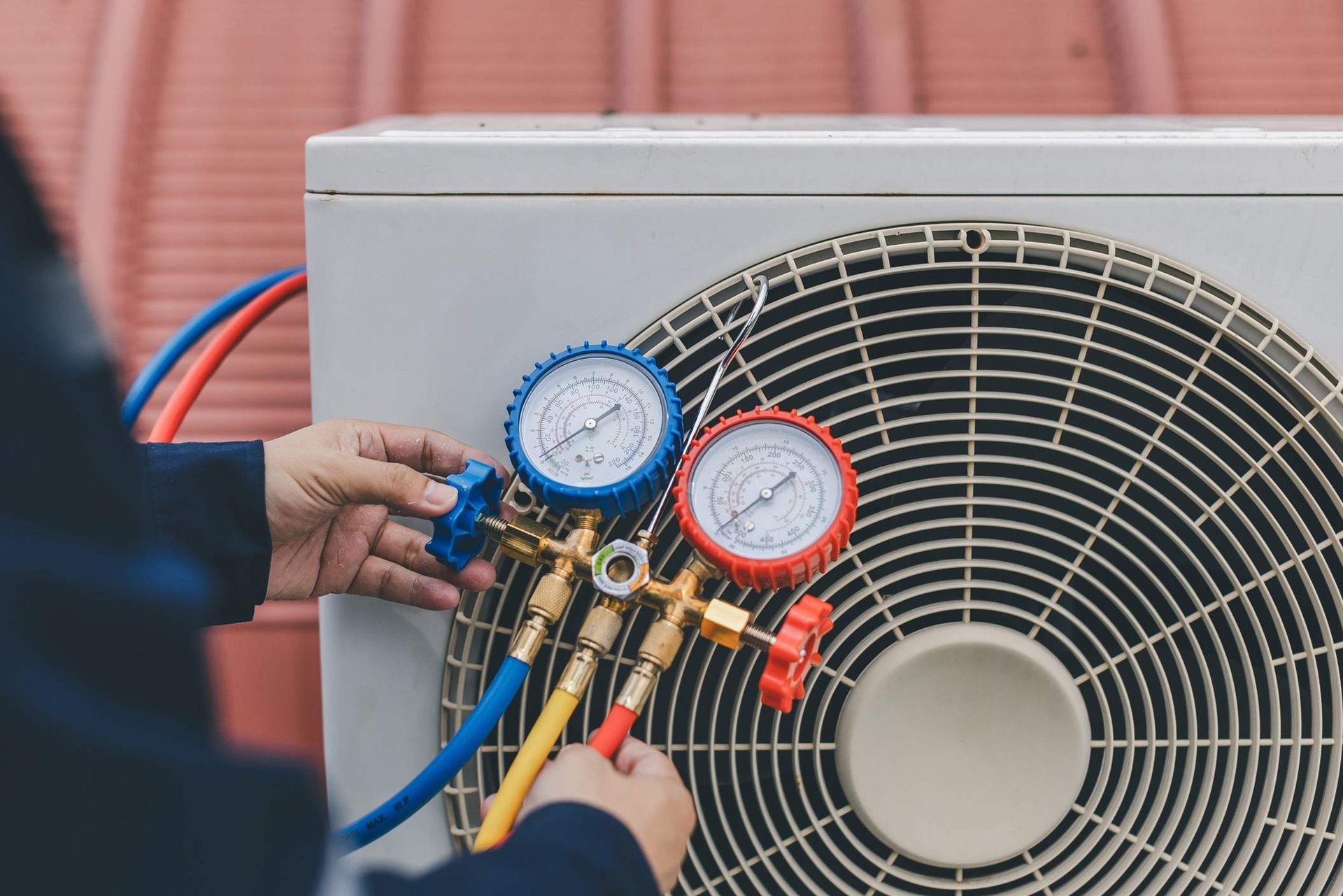 Technician checking air conditioner with manifold gauge.
