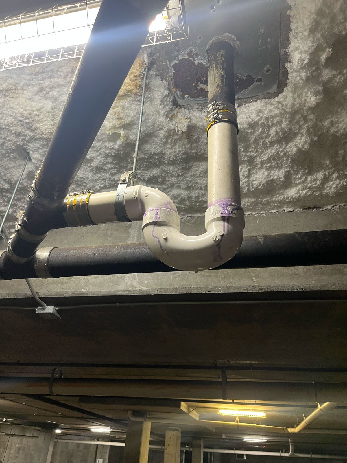 A bunch of pipes are hanging from the ceiling of a building.