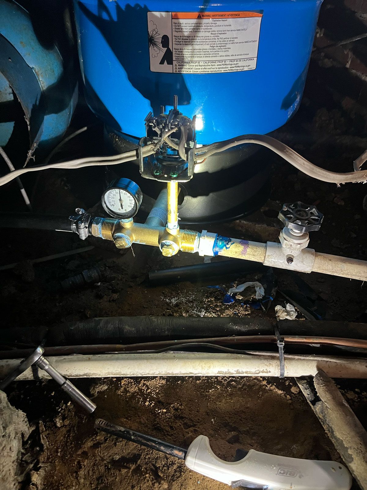 A water pump is sitting in the dirt next to a pipe.