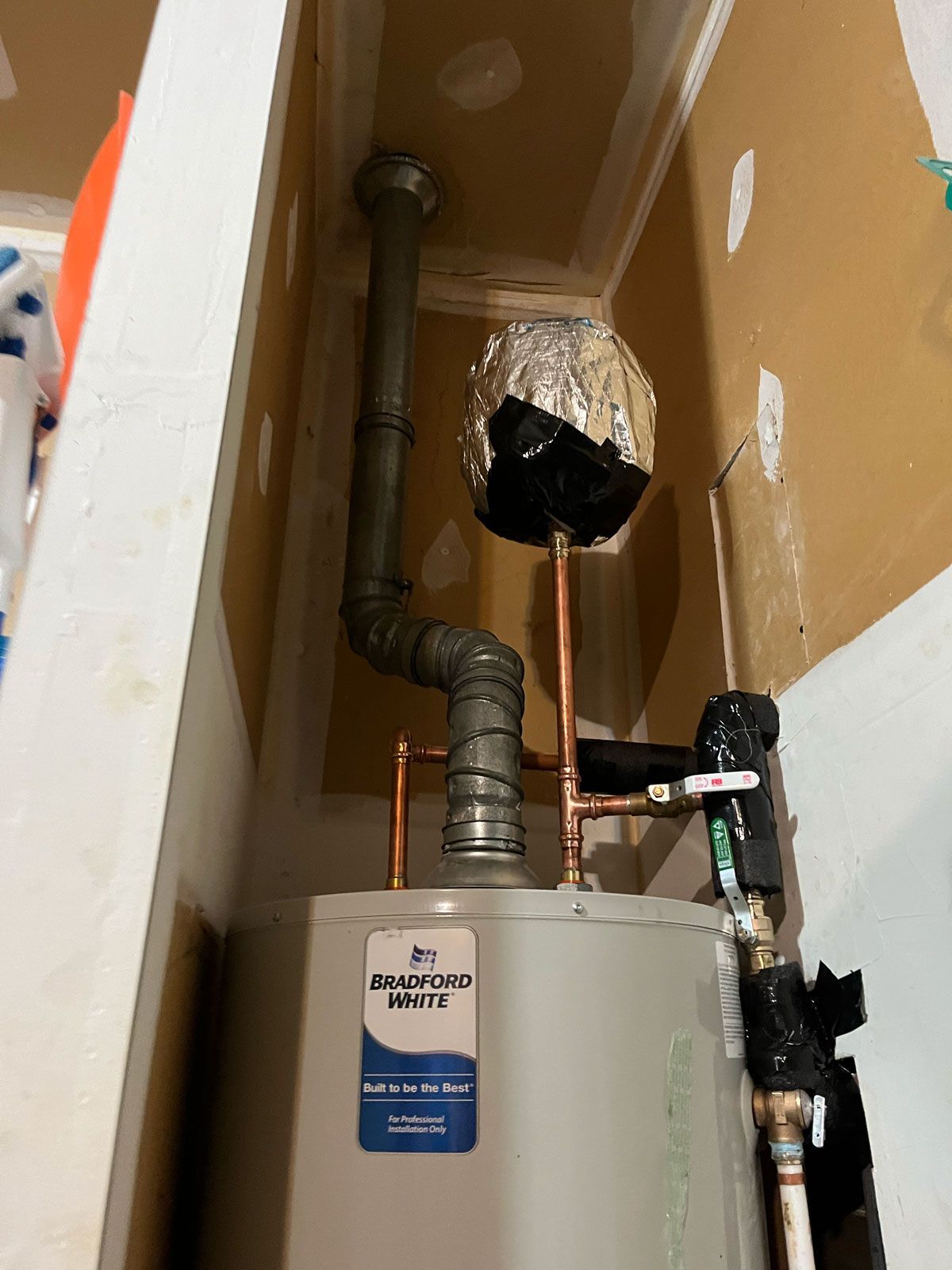 A water heater is sitting in a corner of a room.