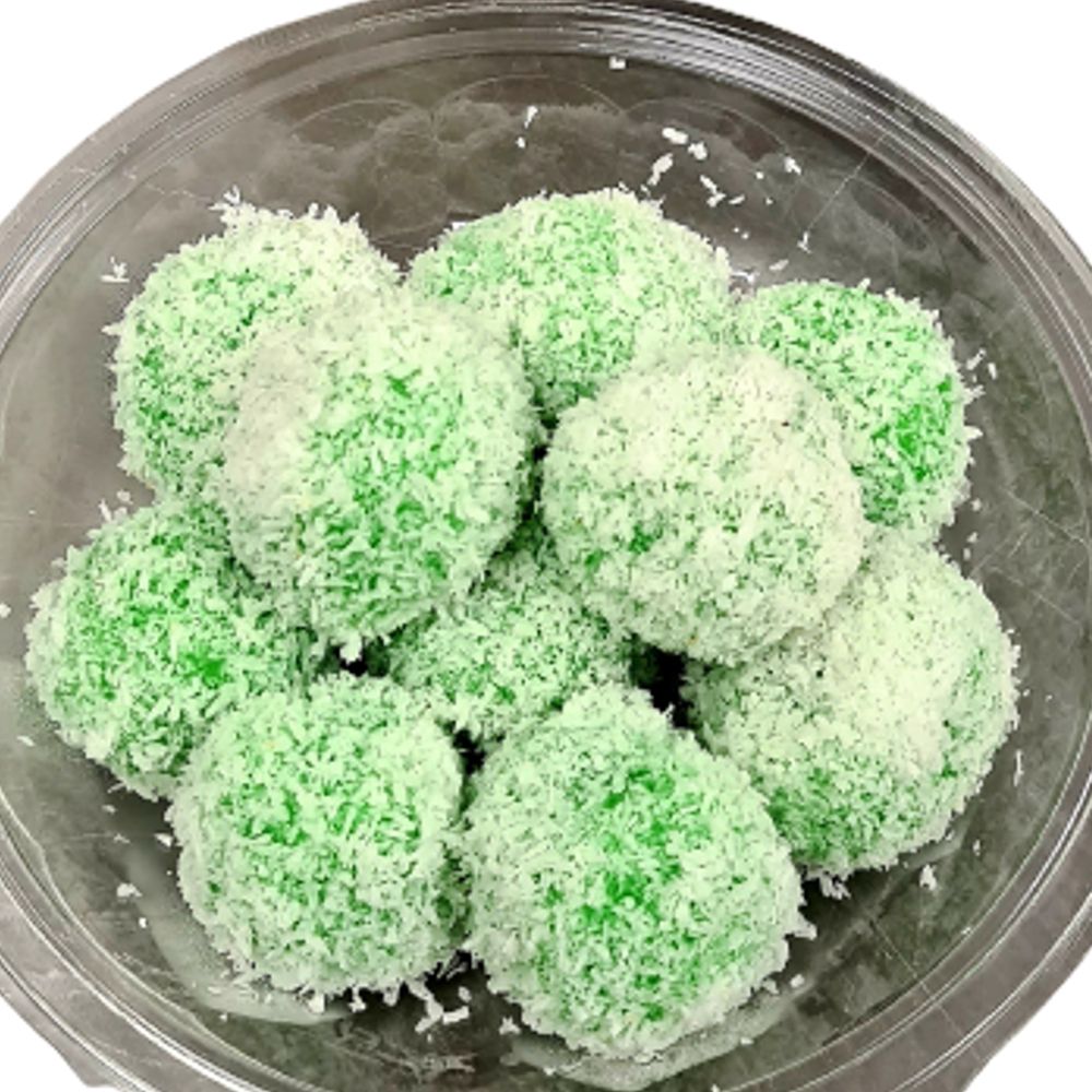 Groene, met kokos bedekte dessertballetjes in een doorzichtige plastic verpakking.