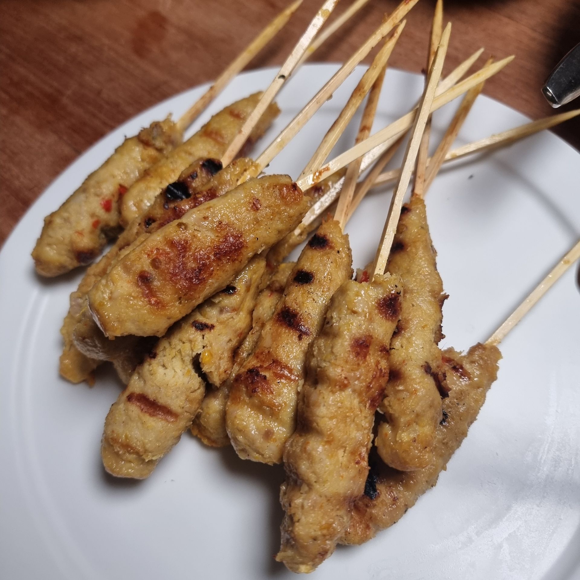 Gegrilde kipsat&eacute;spiesjes op een wit bord.
