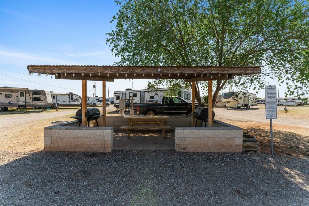 there is a picnic table under a shelter in the middle of a parking lot .