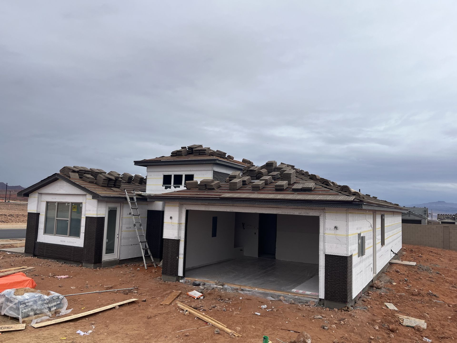 Roofer in tan shirt and pants, nailing shingles to a brown log cabin roof.