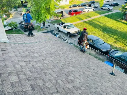 Roofers working on a residential roof, with cars and street in the background.