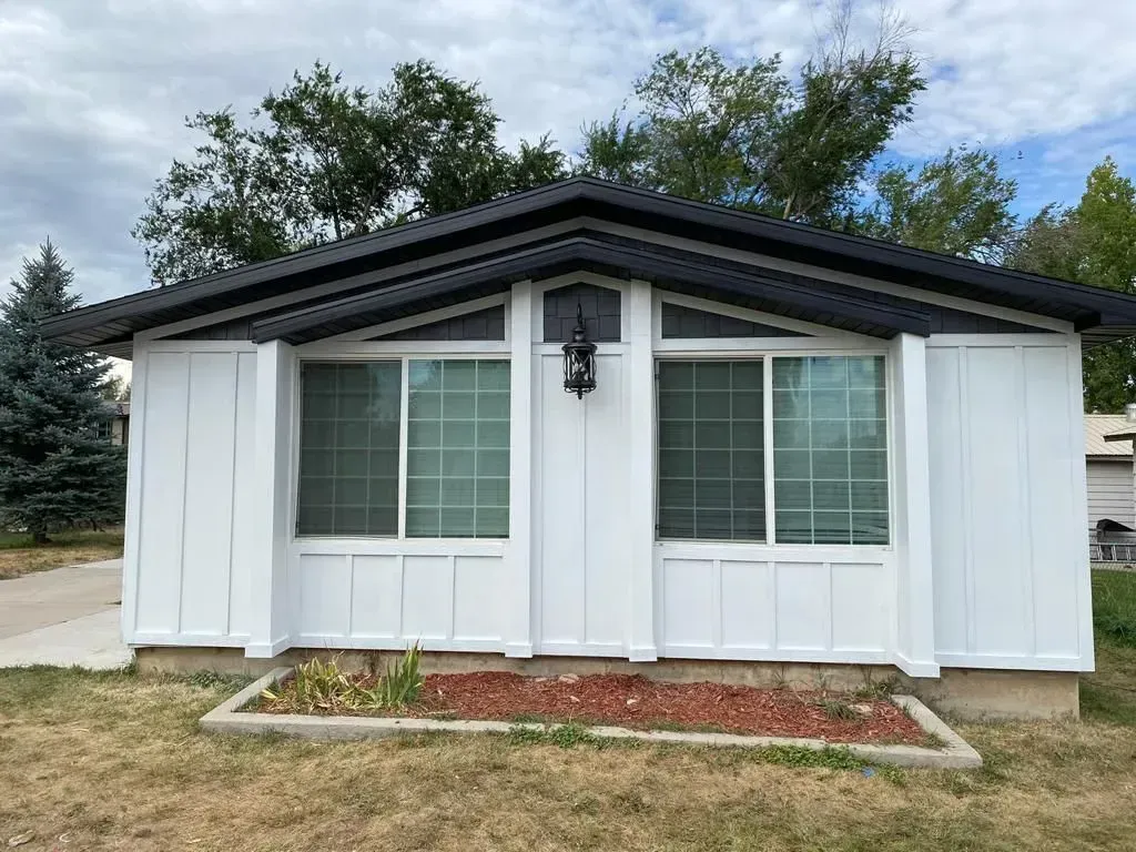 Dark brown asphalt shingle roof on a house with vents, against a backdrop of trees and a mountain.