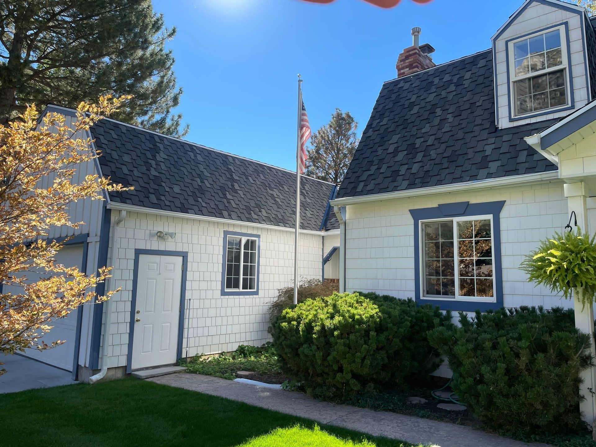Copper gutters on a cabin roof with trees in the background. Deck with chairs, a grill, and firewood.