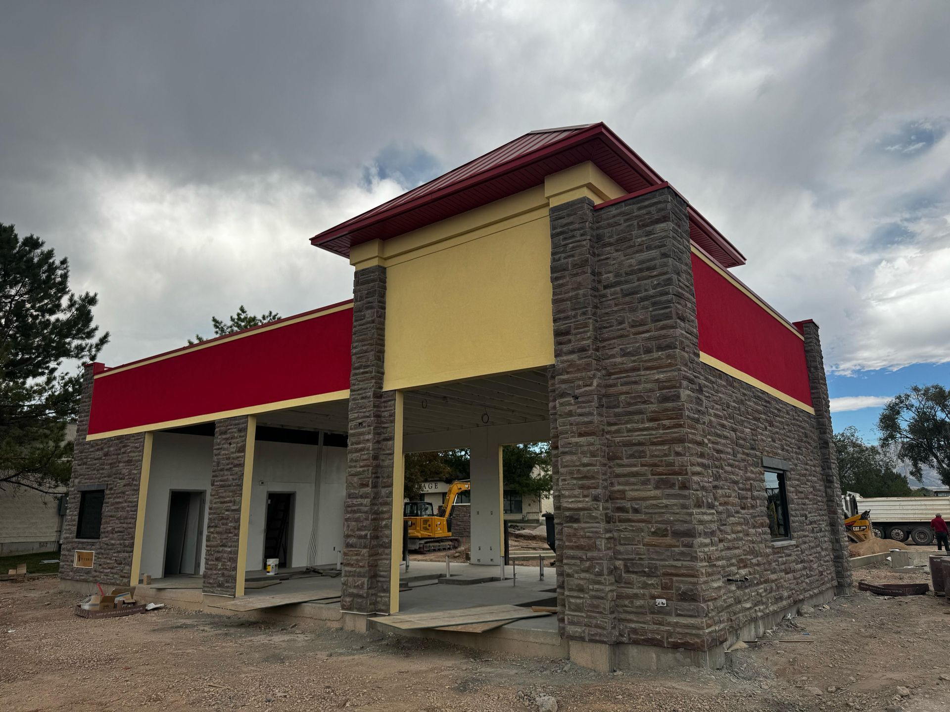 Cabin with brown metal roof, log siding, green door, windows, and a blue sky.