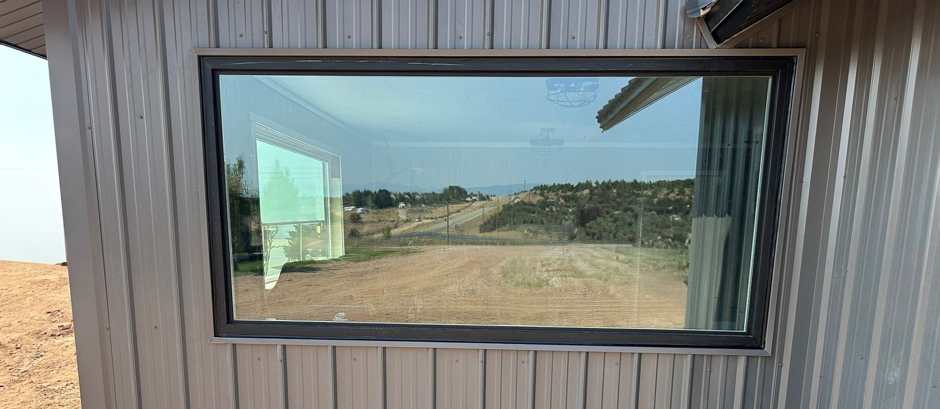 Two dormer windows with wood frames on a slate roof under a blue sky.