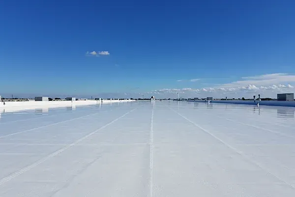 White flat commercial rooftop against a clear blue sky.