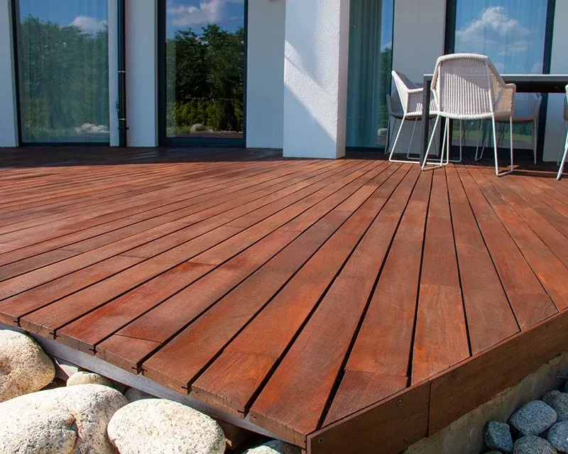 Wooden deck with outdoor furniture, next to a modern house.