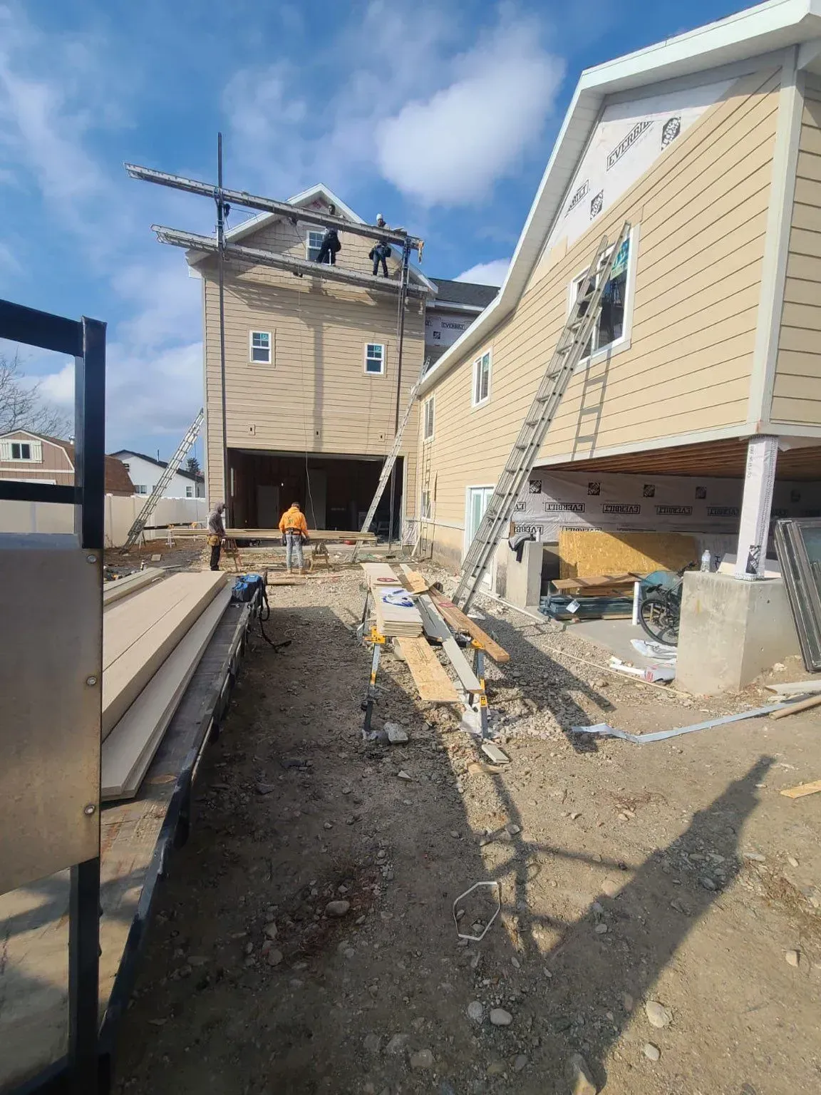 Construction site with two buildings; a worker stands in between them.